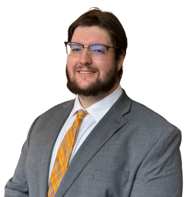 picture of Thomas Burleigh, from chest height upwards; he has short dark hair, a dark beard, is wearing glasses, a white shirt, a grey suit jacket, and an orange tie